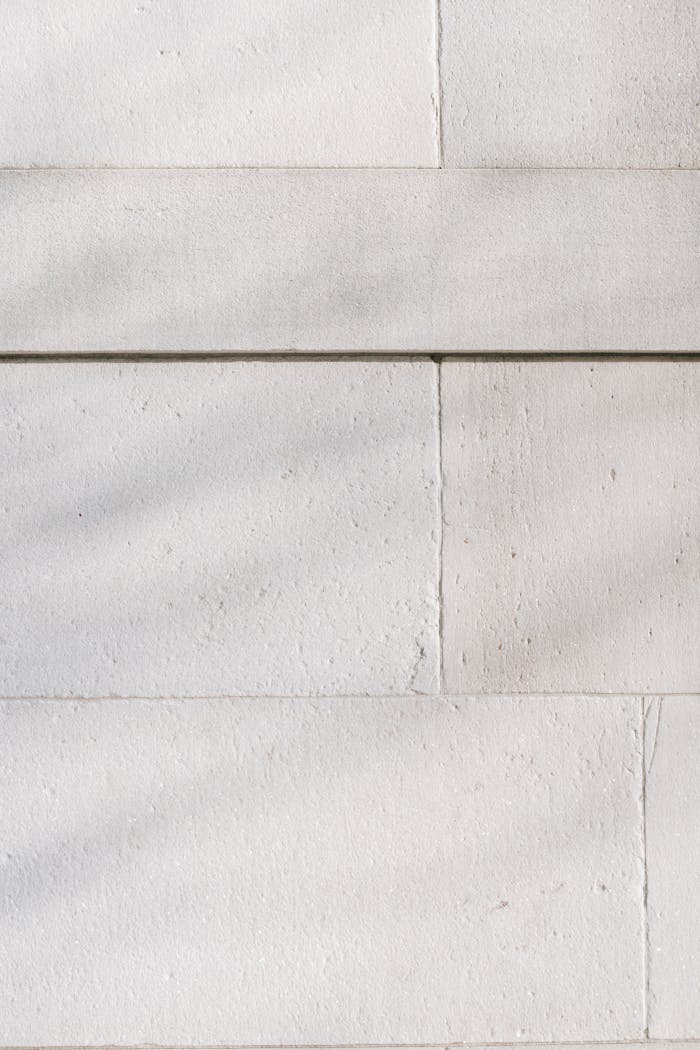 Abstract background of surface of textured white stone wall with scratches on sunny day